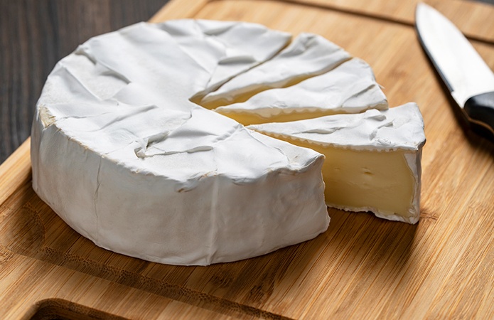 Formaggio a pasta molle su tagliere, potenzialmente a rischio di contaminazione da STEC se prodotto con latte crudo, simbolo dell'articolo del blog che tratta la tematica del Escherichia coli produttore di Shiga tossine nei formaggi, relativo alla business unit food di Lifeanalytics