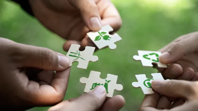 Metafora delle certificazioni ambiente ed energia: mani con puzzle che rappresentano elementi di ambiente, sostenibilità