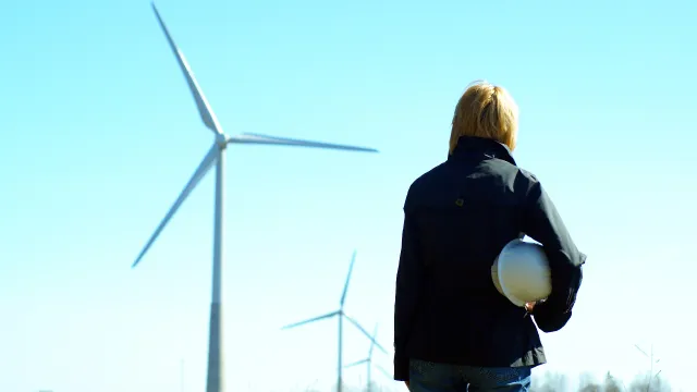 Operatore nell’atto di guardare le pale eoliche nell’atto di produrre energia sostenibile.
