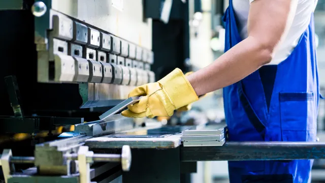 Lavoratore intento a effettuare un lavoro con un macchinario che rispetta le normative in merito alla sicurezza delle macchine.