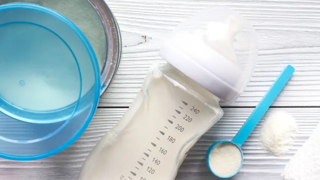 Latte in polvere in contenitore di latta, misurino e all’interno di un biberon pronto per raccogliere il campionamento per le analisi di laboratorio su baby food, novel food o integratori alimentari.