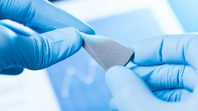 Mani guantate intente a testare un nuovo polimero per un test di tecnologia dei materiali