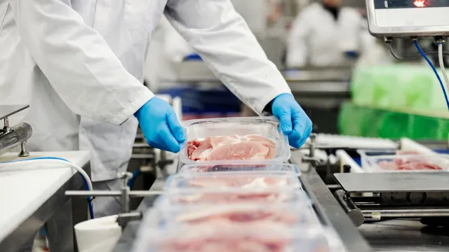 Operatore che sposta una vaschetta piena di carne che deve essere sottoposta ad analisi per la verifica della presenza di NIAS