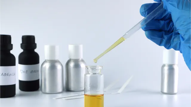 Operatore di laboratorio intento a prelevare un campione di parfume-profumo per effettuare analisi 